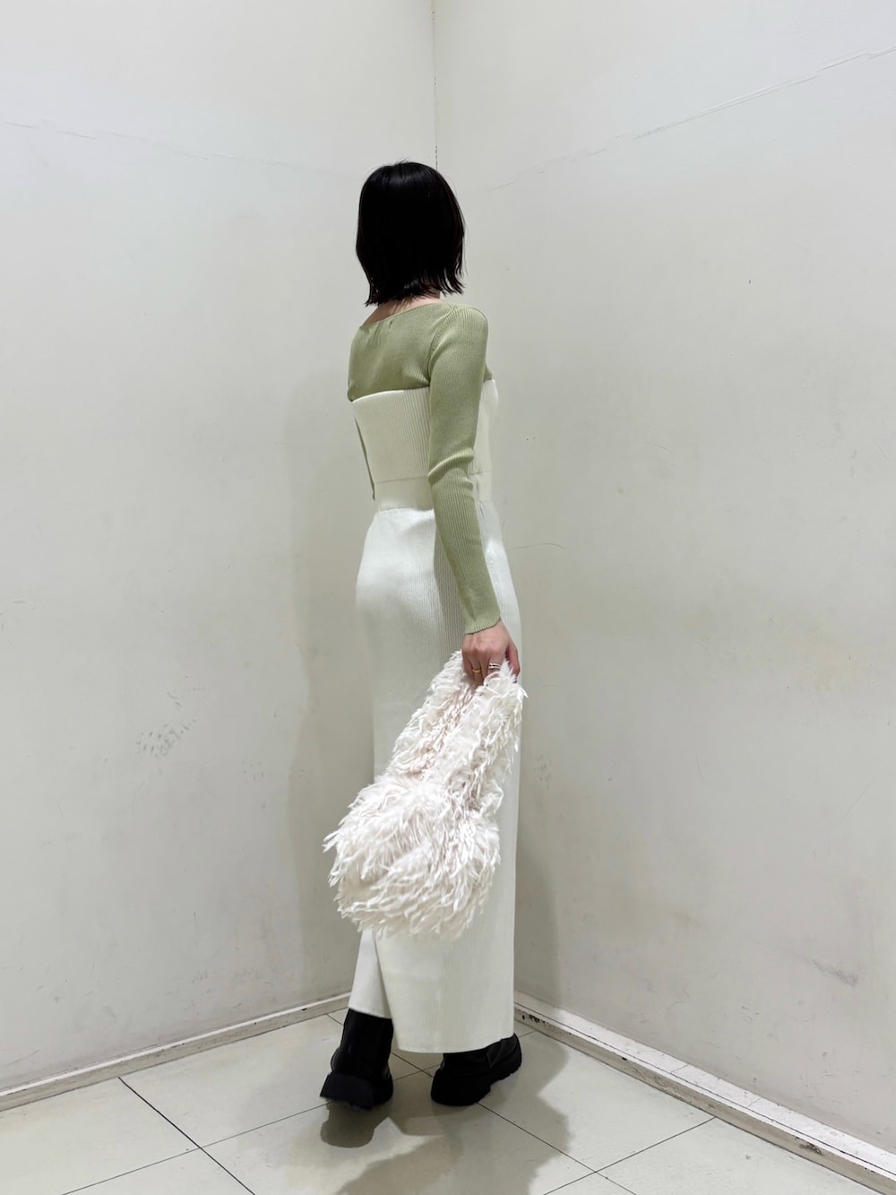 ホワイト系のワンピース、グリーン系のニット/セーター、ホワイト系のハンドバッグを着用したレディースの冬コーディネートの3枚目の写真