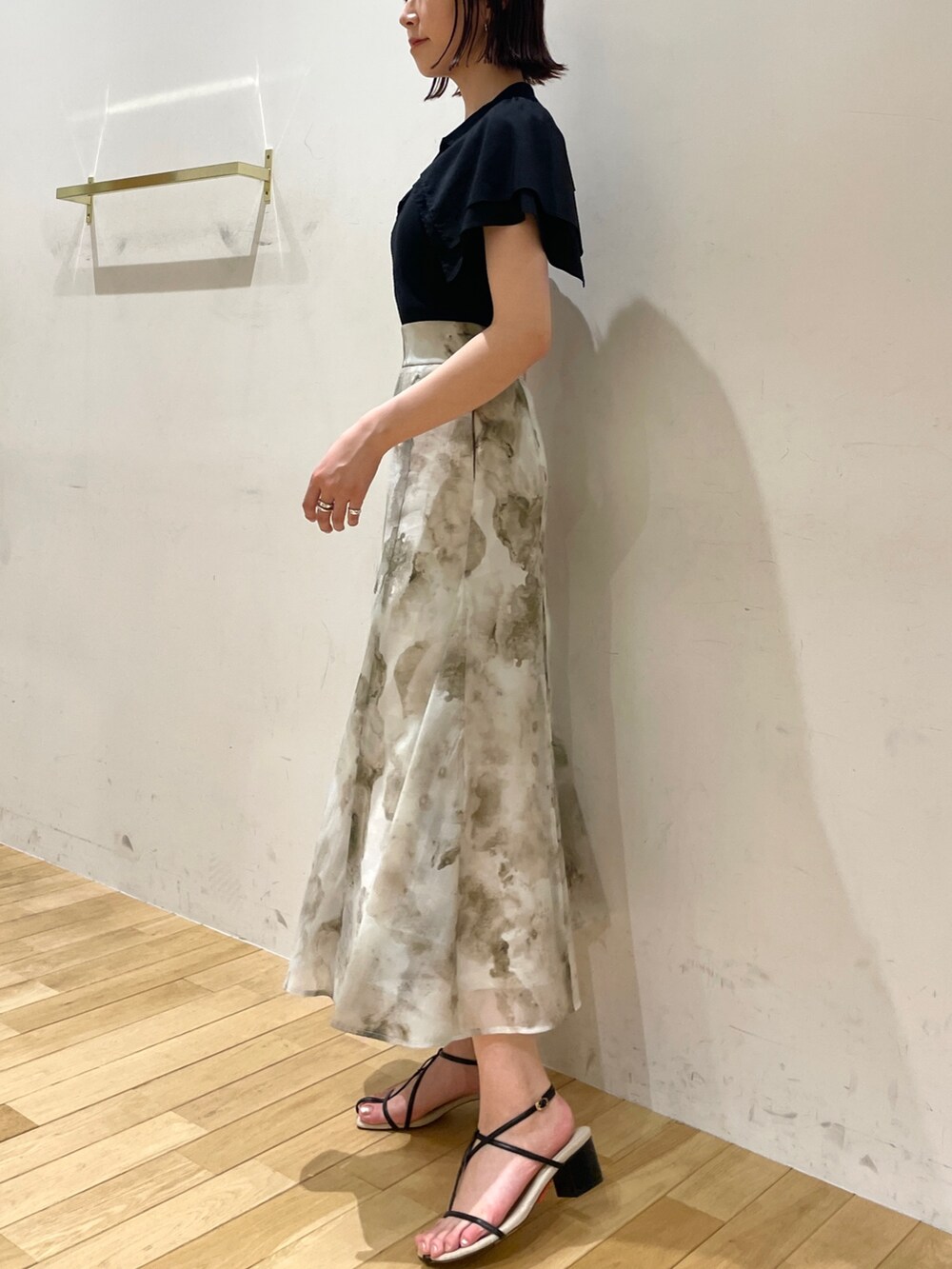 ブラック系のサンダル、グレー系のスカート、ブラック系のニット/セーターを着用したレディースの夏コーディネートの5枚目の写真