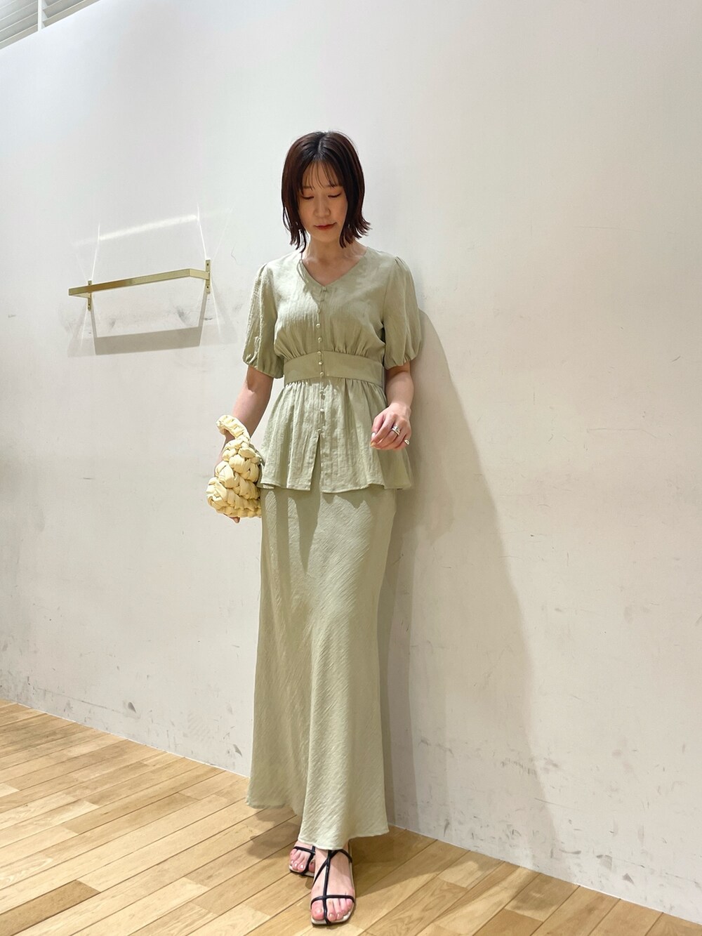 ベージュ系のハンドバッグ、ブラック系のサンダル、グリーン系のスカートを着用したレディースの夏コーディネートの2枚目の写真