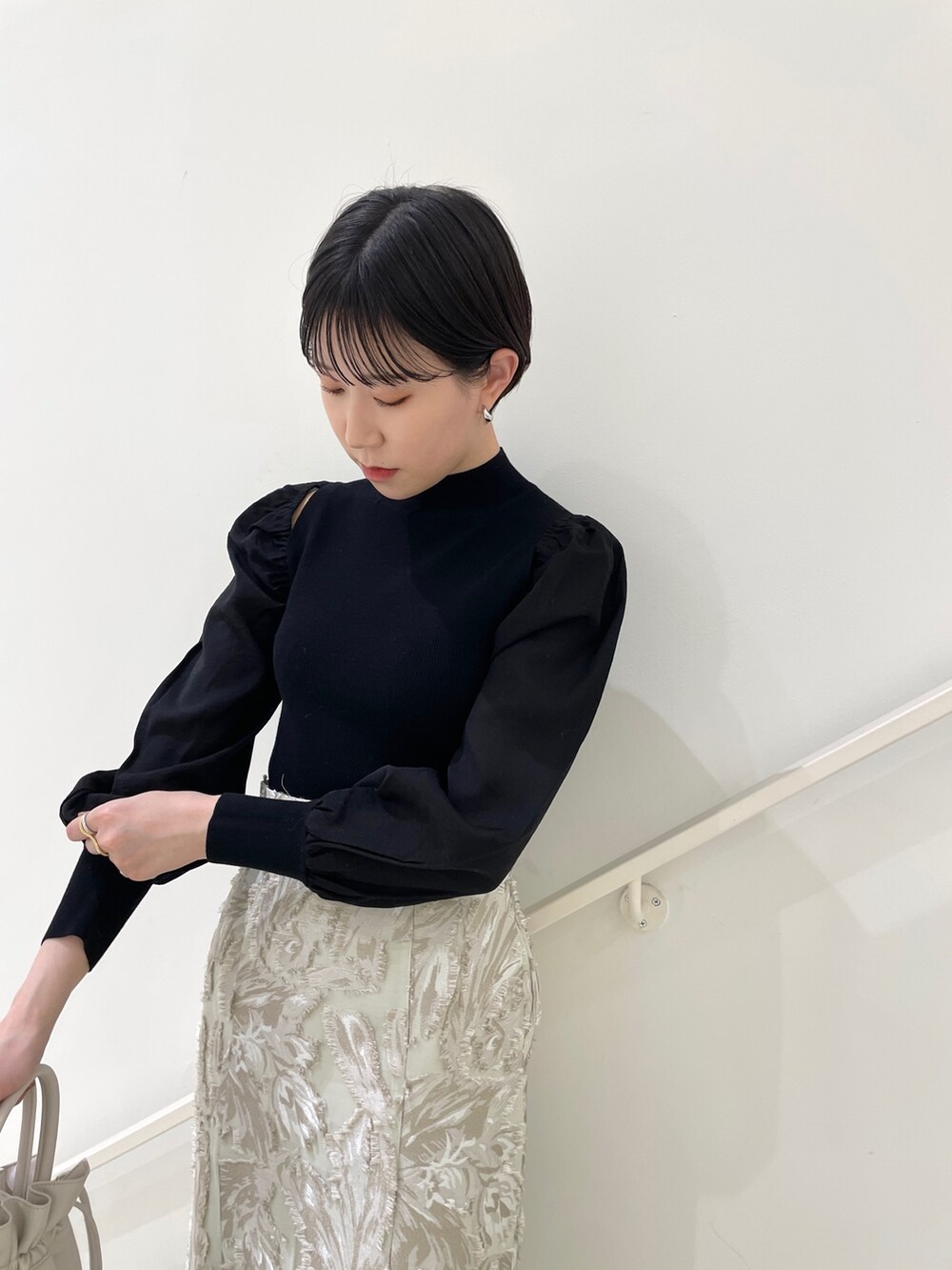 ブラック系のニット/セーター、ベージュ系のスカート、ホワイト系のハンドバッグを着用したレディースの冬コーディネートの5枚目の写真