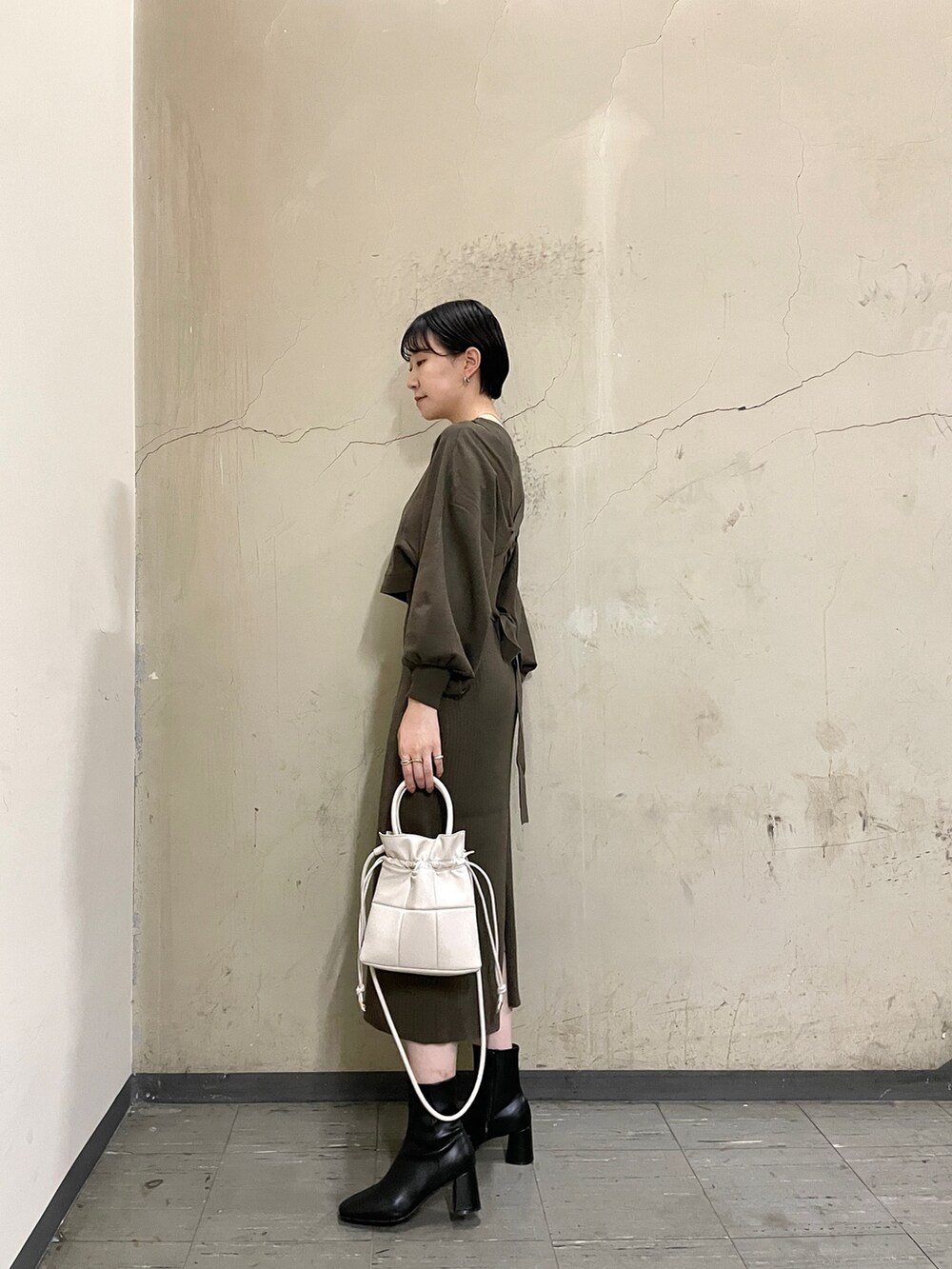 ブラウン系のワンピース、ブラック系のブーツ、ホワイト系のハンドバッグを着用したレディースの秋コーディネートの3枚目の写真