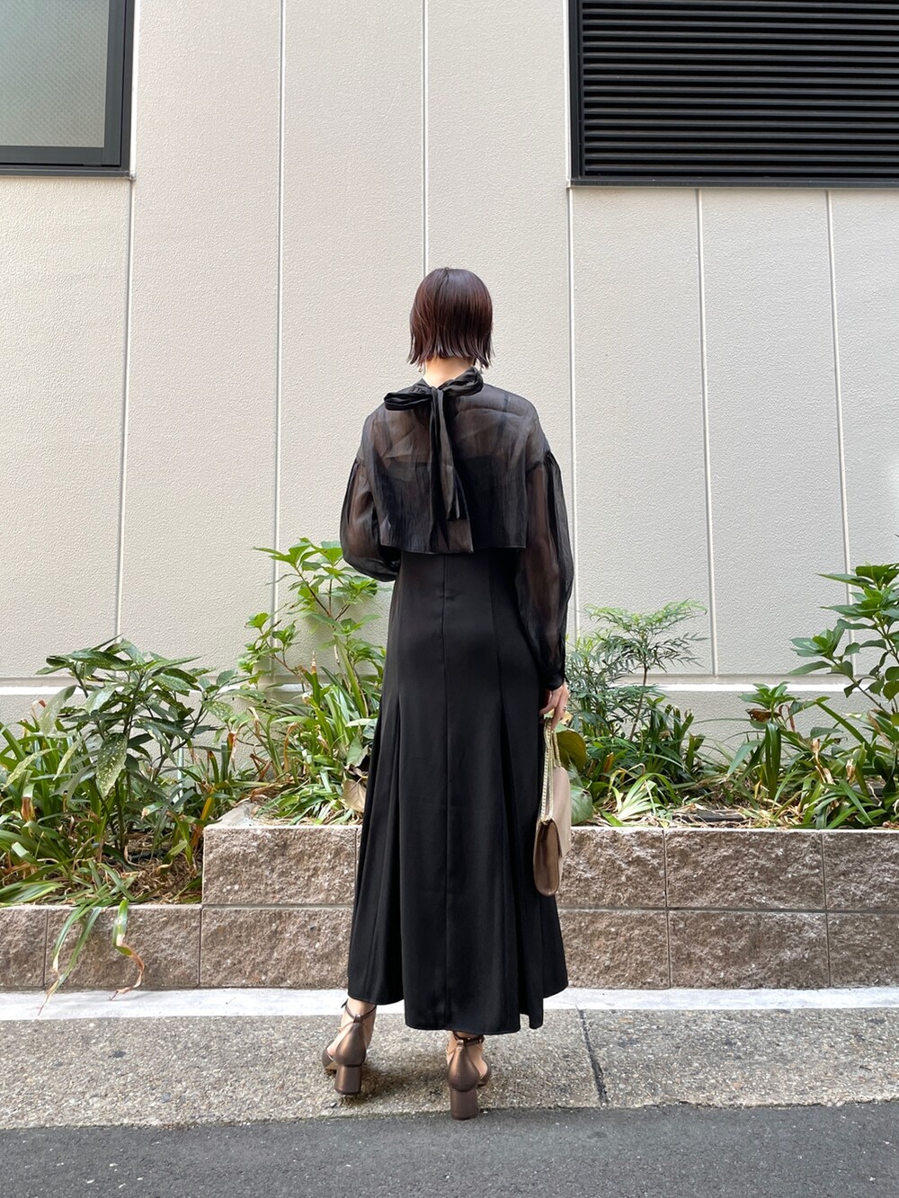 ブラック系のドレス、その他のパンプス、ゴールド系のハンドバッグを着用したレディースの秋コーディネートの5枚目の写真