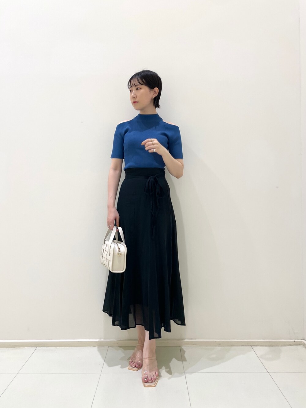 ブラック系のスカート、ホワイト系のショルダーバッグ、その他のサンダルを着用したレディースの夏コーディネートの2枚目の写真