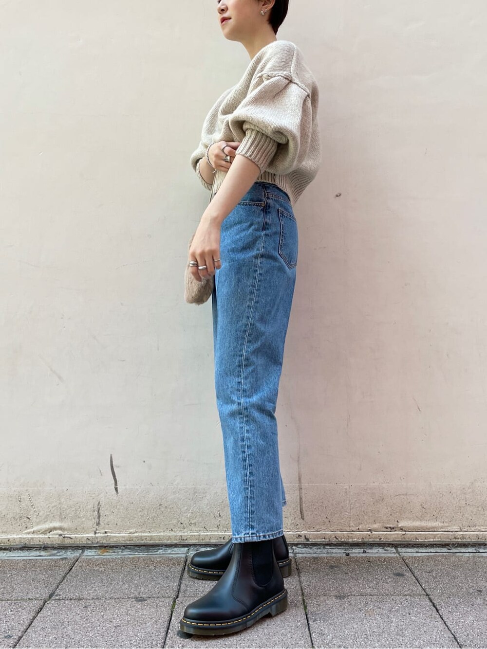 ブラック系のブーツ、ブルー系のデニムパンツ、ホワイト系のニット/セーターを着用したレディースの冬コーディネートの2枚目の写真