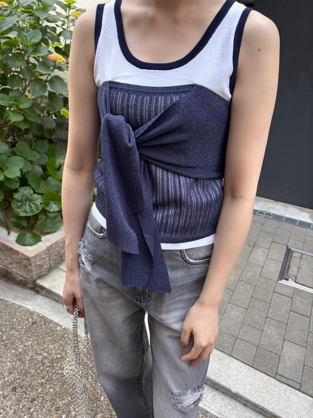 グレー系のデニムパンツ、ホワイト系のニット/セーター、ホワイト系のハンドバッグを着用したレディースの春コーディネートの4枚目の写真