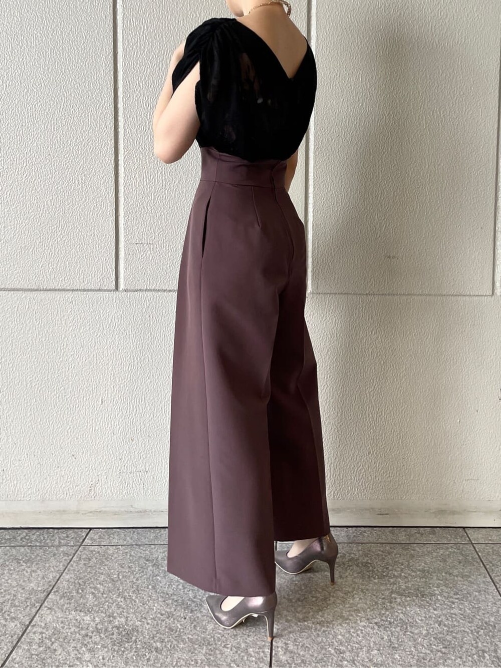 パープル系のパンツドレス、シルバー系のパンプス、ベージュ系のクラッチバッグを着用したレディースの春コーディネートの6枚目の写真