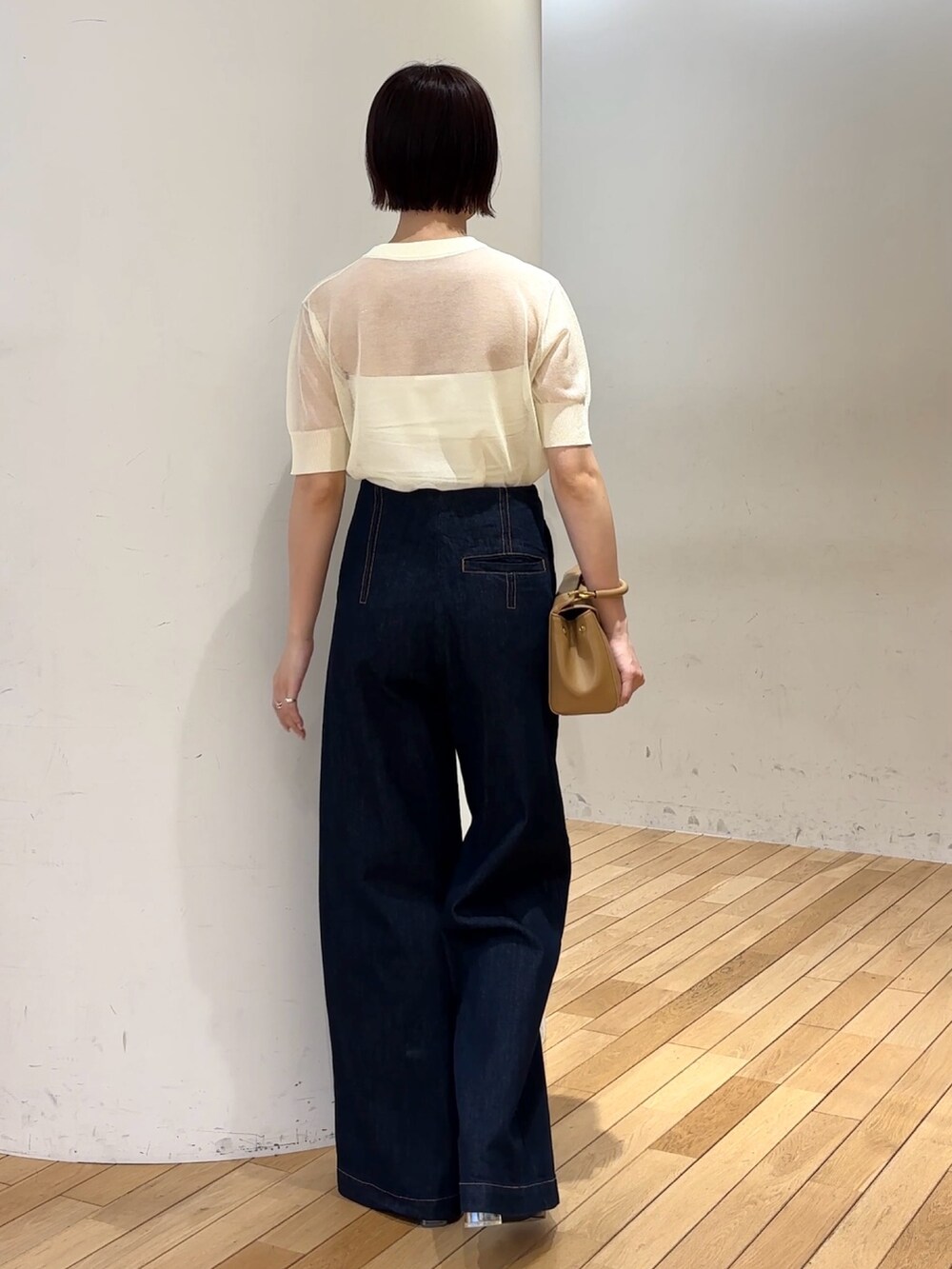ブルー系のデニムパンツ、イエロー系のハンドバッグ、ブラック系のサンダルを着用したレディースの春コーディネートの3枚目の写真