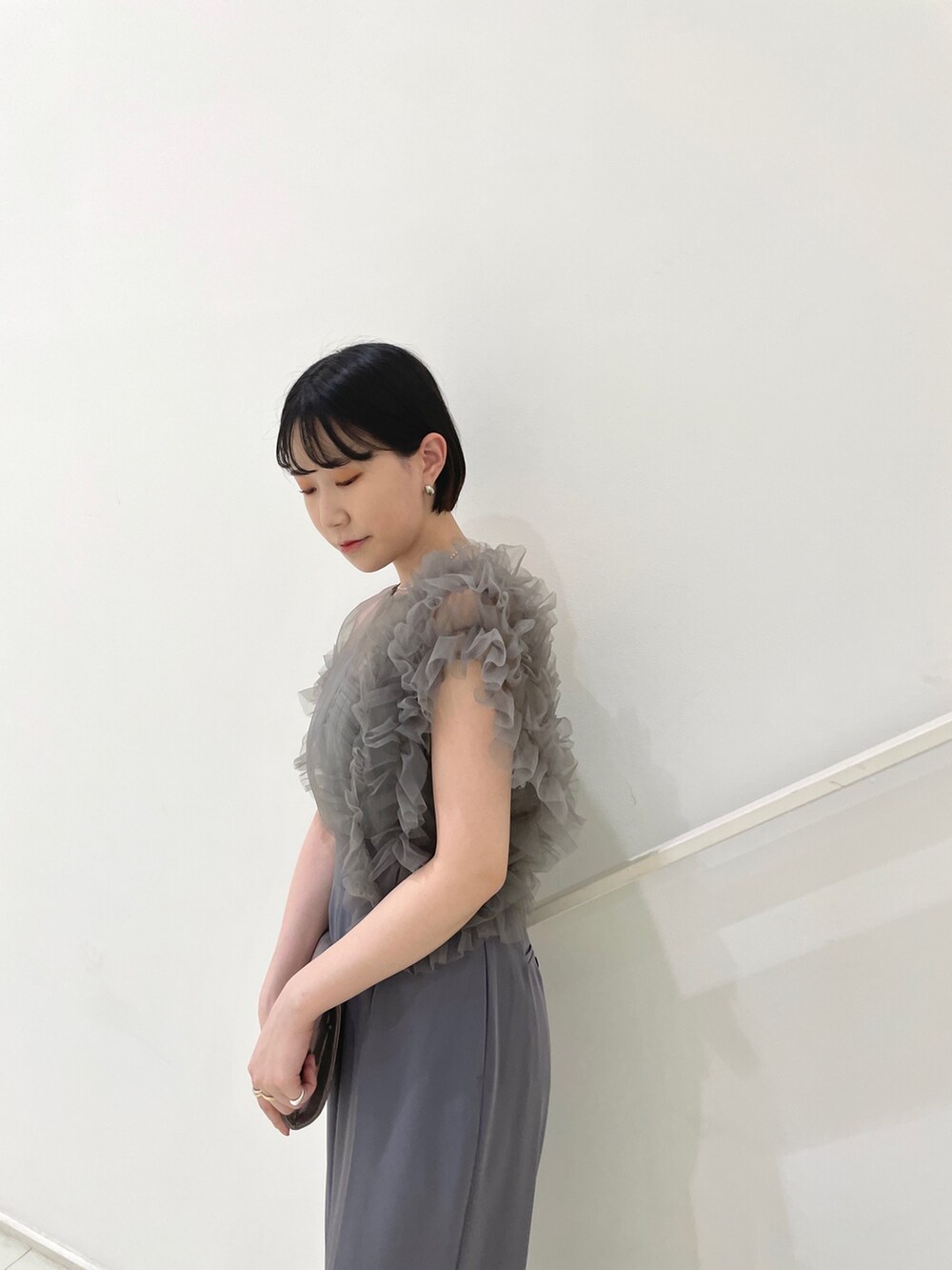 グレー系のパンツドレス、シルバー系のハンドバッグ、シルバー系のパンプスを着用したレディースの春コーディネートの7枚目の写真