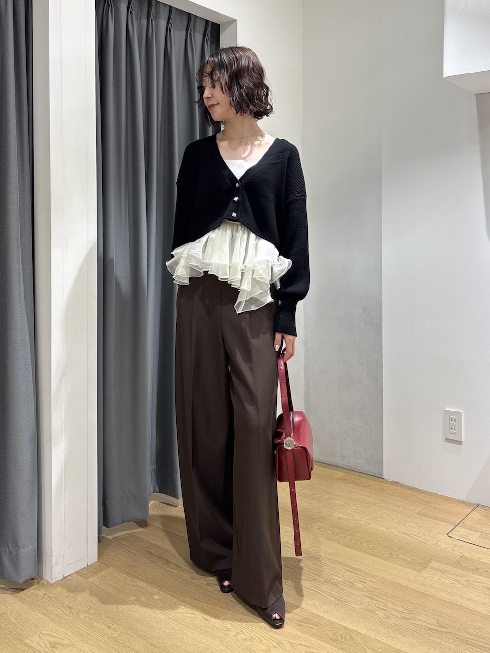 ブラウン系のその他パンツ、ブラック系のカーディガン/ボレロ、レッド系のハンドバッグを着用したレディースの秋コーディネートの2枚目の写真