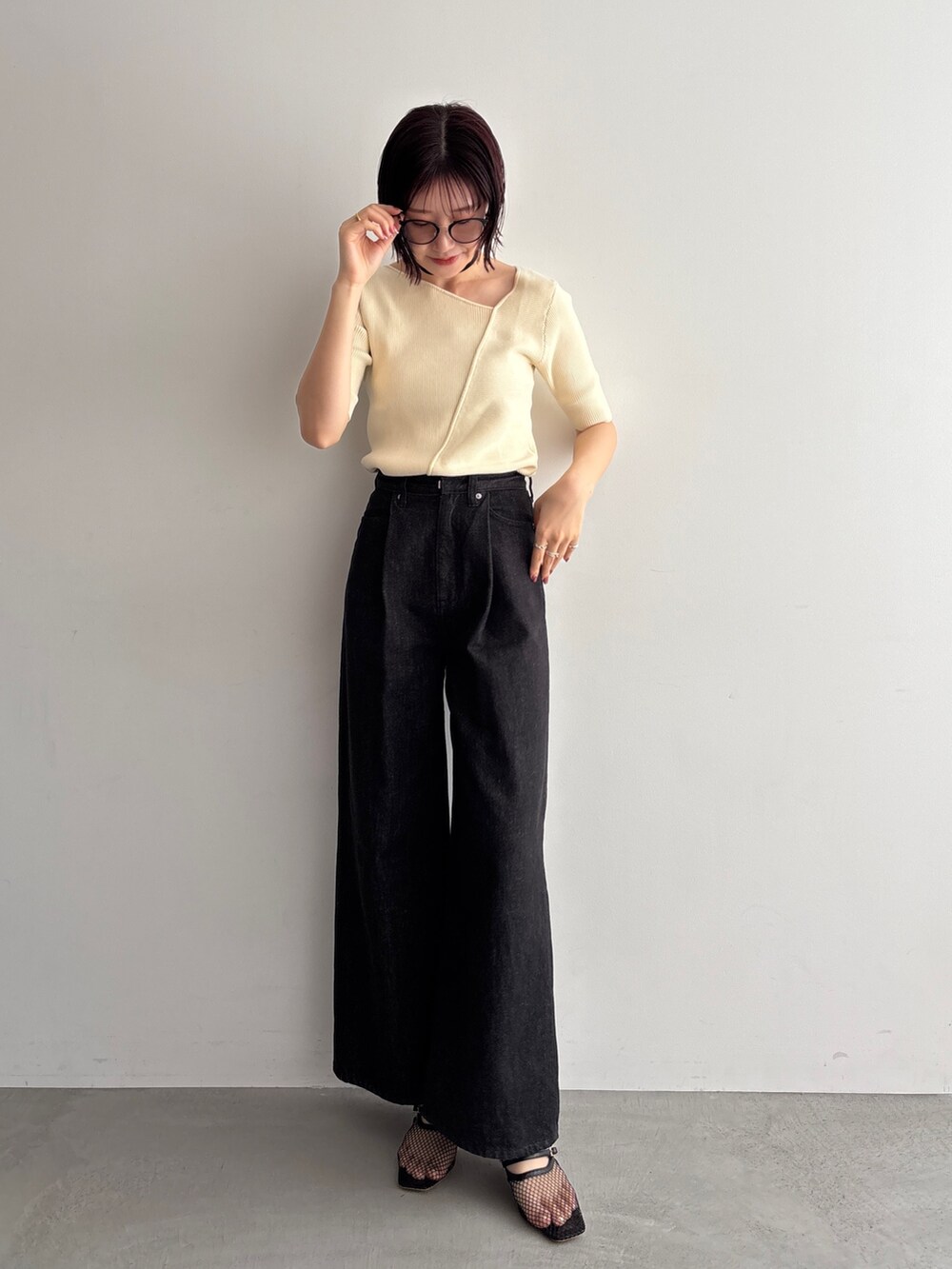 ブラック系のデニムパンツ、ホワイト系のニット/セーターを着用したレディースの夏コーディネートの2枚目の写真