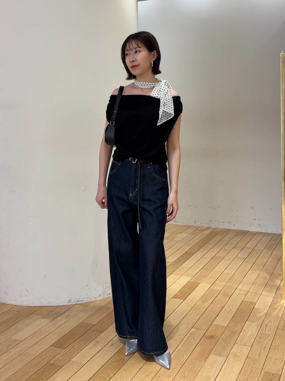 ブルー系のデニムパンツ、ブラック系のハンドバッグ、シルバー系のパンプスを着用したレディースの夏コーディネートの5枚目の写真