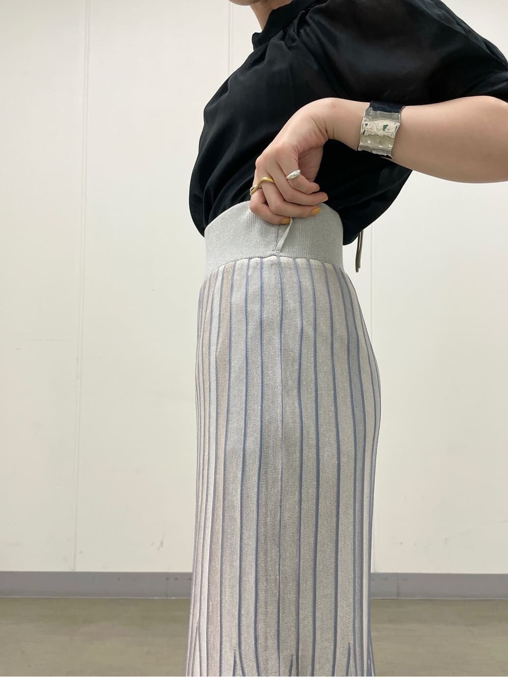 ブルー系のスカート、ホワイト系のサンダル、ブラック系のシャツ/ブラウスを着用したレディースの夏コーディネートの6枚目の写真