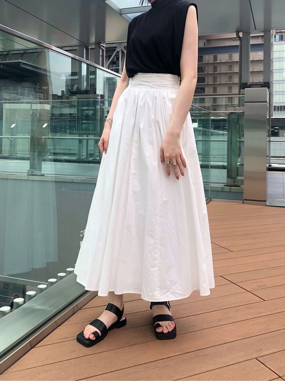 ブラック系のサンダル、ホワイト系のスカート、ブラック系のニット/セーターを着用したレディースの夏コーディネートの7枚目の写真