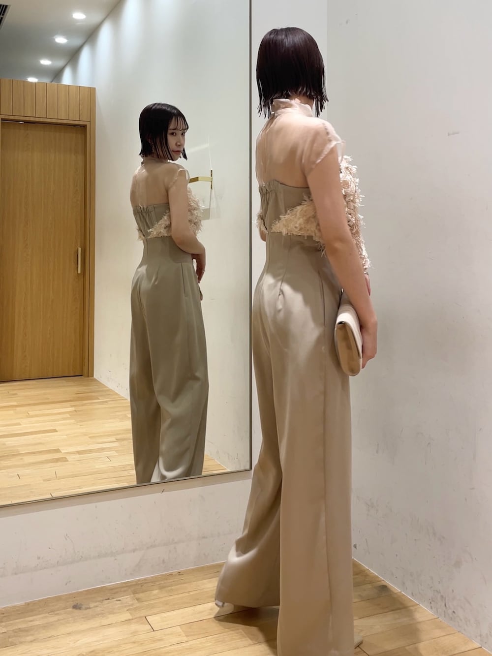 ベージュ系のパンプス、ベージュ系のパンツドレス、ベージュ系のクラッチバッグを着用したレディースの冬コーディネートの4枚目の写真