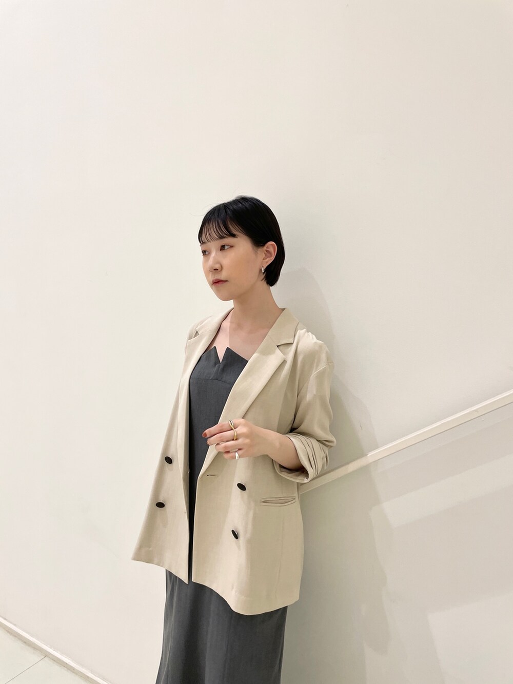 ベージュ系のテーラードジャケット、グレー系のワンピース、ブラック系のサンダルを着用したレディースの春コーディネートの6枚目の写真