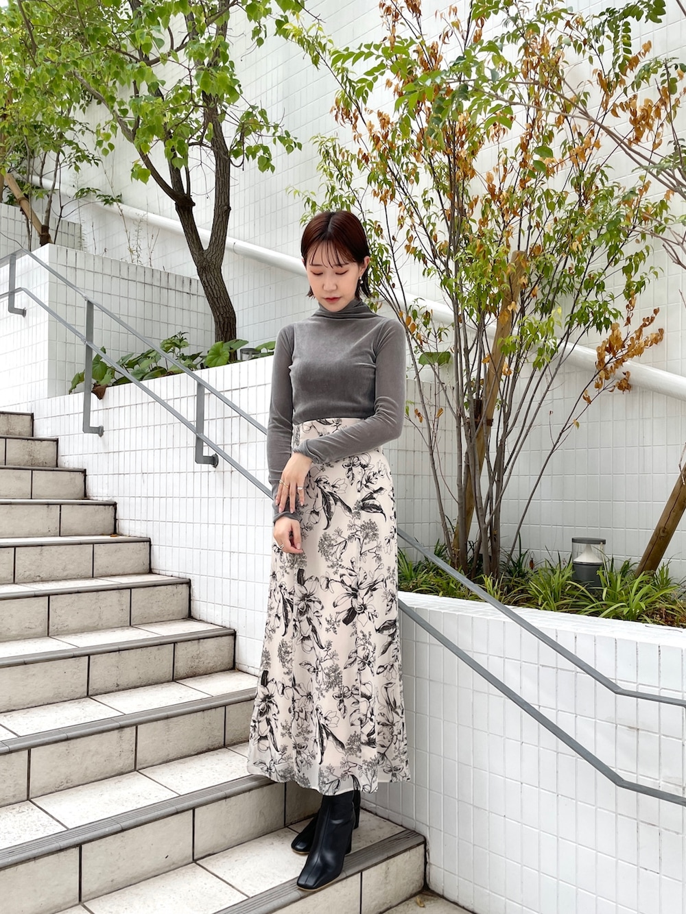 グレー系のTシャツ/カットソー、ホワイト系のスカート、ブラック系のブーツを着用したレディースの秋コーディネートの2枚目の写真