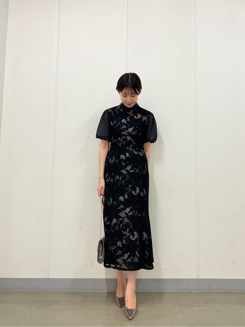 シルバー系のクラッチバッグ、シルバー系のパンプス、ブラック系のドレスを着用したレディースの夏コーディネートの2枚目の写真