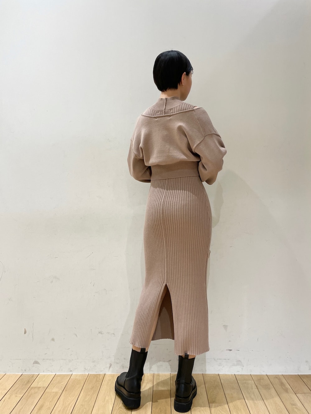 ベージュ系のワンピース、ホワイト系のハンドバッグ、ブラック系のブーツを着用したレディースの冬コーディネートの5枚目の写真