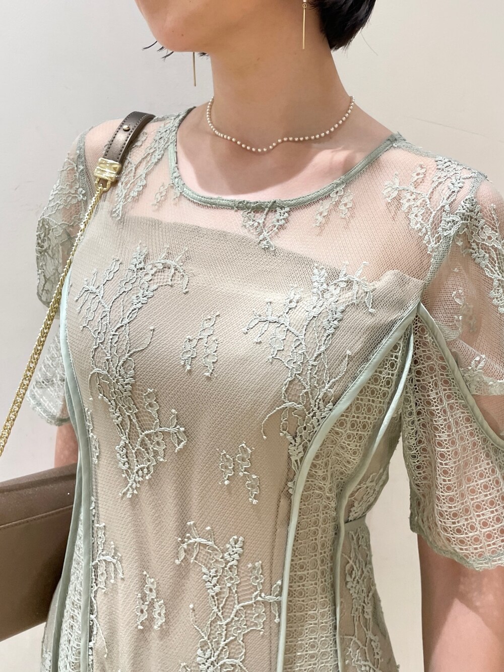 グリーン系のドレス、ゴールド系のハンドバッグ、ゴールド系のパンプスを着用したレディースの夏コーディネートの7枚目の写真