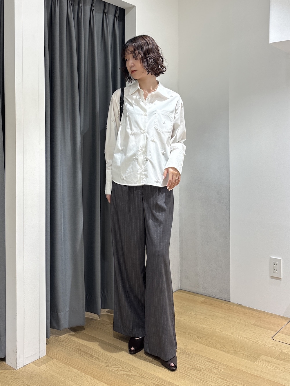 グレー系のその他パンツ、ホワイト系のシャツ/ブラウス、ブラック系のハンドバッグを着用したレディースの秋コーディネートの2枚目の写真