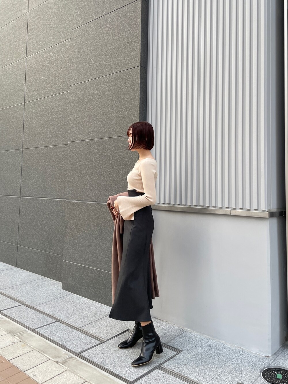 ホワイト系のニット/セーター、ブラウン系のチェスターコート、グレー系のスカートを着用したレディースの冬コーディネートの3枚目の写真