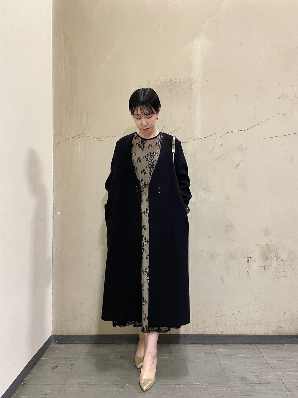 ブラック系のドレス、ゴールド系のハンドバッグ、ゴールド系のパンプスを着用したレディースの秋コーディネートの9枚目の写真