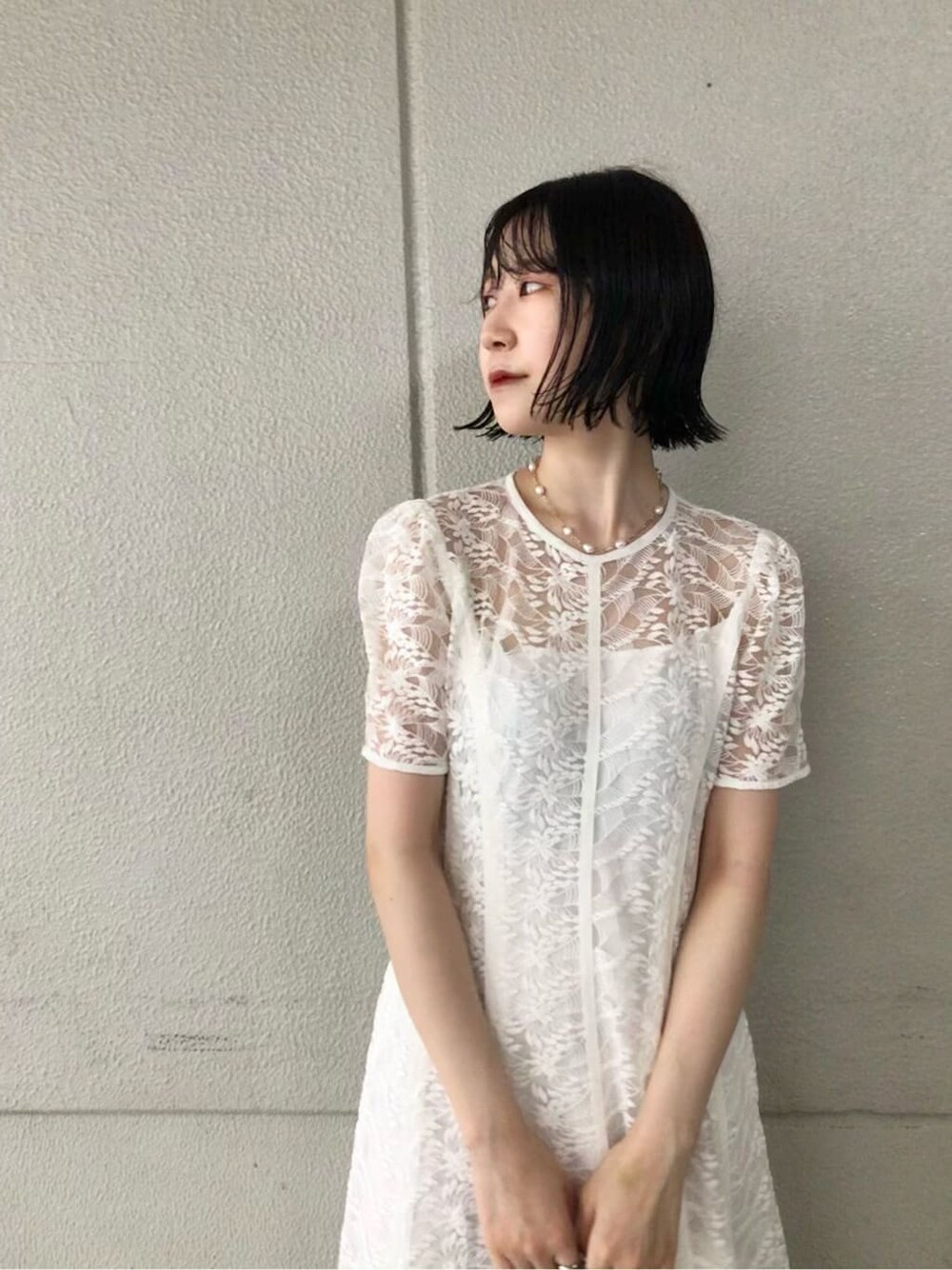 ホワイト系のドレス、ゴールド系のパンプス、ゴールド系のクラッチバッグを着用したレディースの夏コーディネートの3枚目の写真