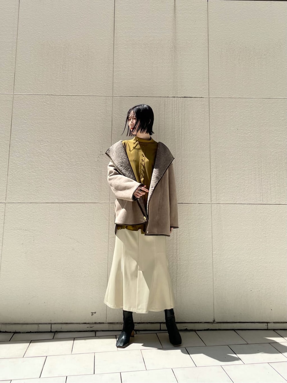 ホワイト系のスカート、ブラック系のその他シューズ、ベージュ系のその他アウターを着用したレディースの秋コーディネートの7枚目の写真