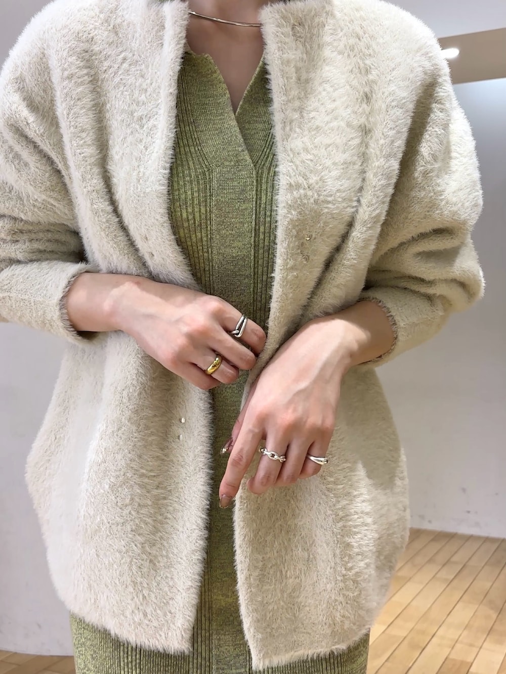 ホワイト系のカーディガン/ボレロ、グリーン系のワンピース、シルバー系のブーツを着用したレディースの冬コーディネートの5枚目の写真