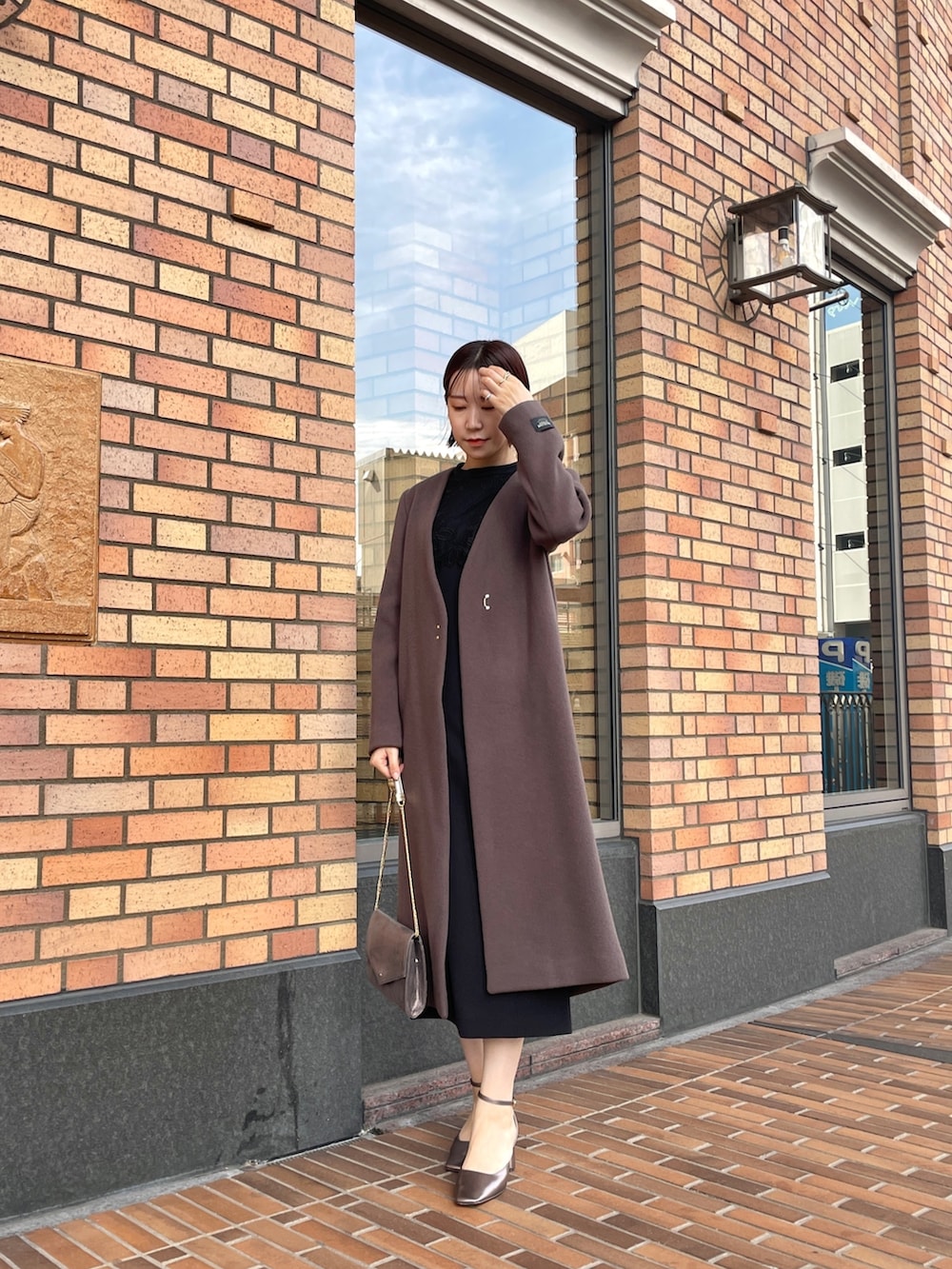 ブラック系のドレス、シルバー系のハンドバッグ、その他のパンプスを着用したレディースの秋コーディネートの7枚目の写真