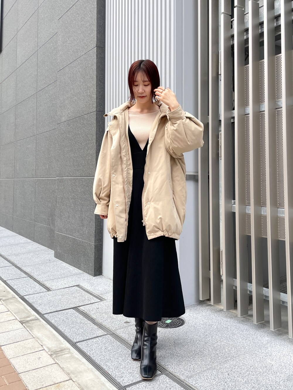 ホワイト系のニット/セーター、ブラック系のジャンパースカート、ブラック系のブーツを着用したレディースの冬コーディネートの7枚目の写真