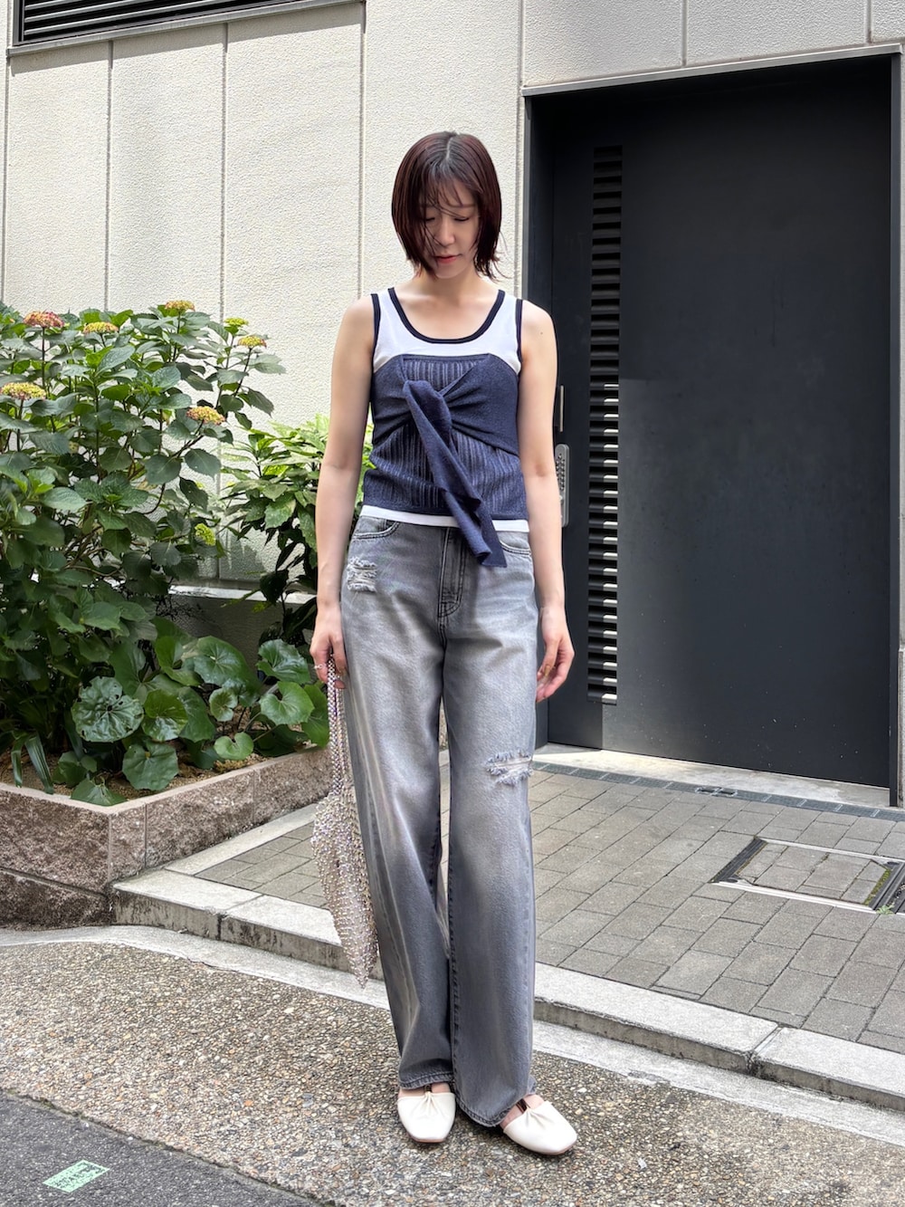 グレー系のデニムパンツ、ホワイト系のニット/セーター、ホワイト系のハンドバッグを着用したレディースの春コーディネートの2枚目の写真
