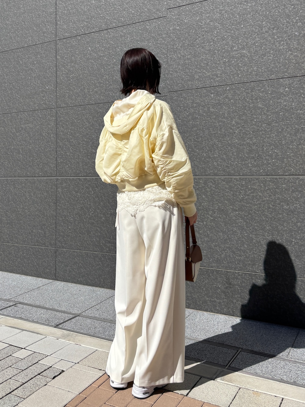 ホワイト系のその他パンツ、ブラウン系のハンドバッグ、イエロー系のブルゾンを着用したレディースの春コーディネートの2枚目の写真