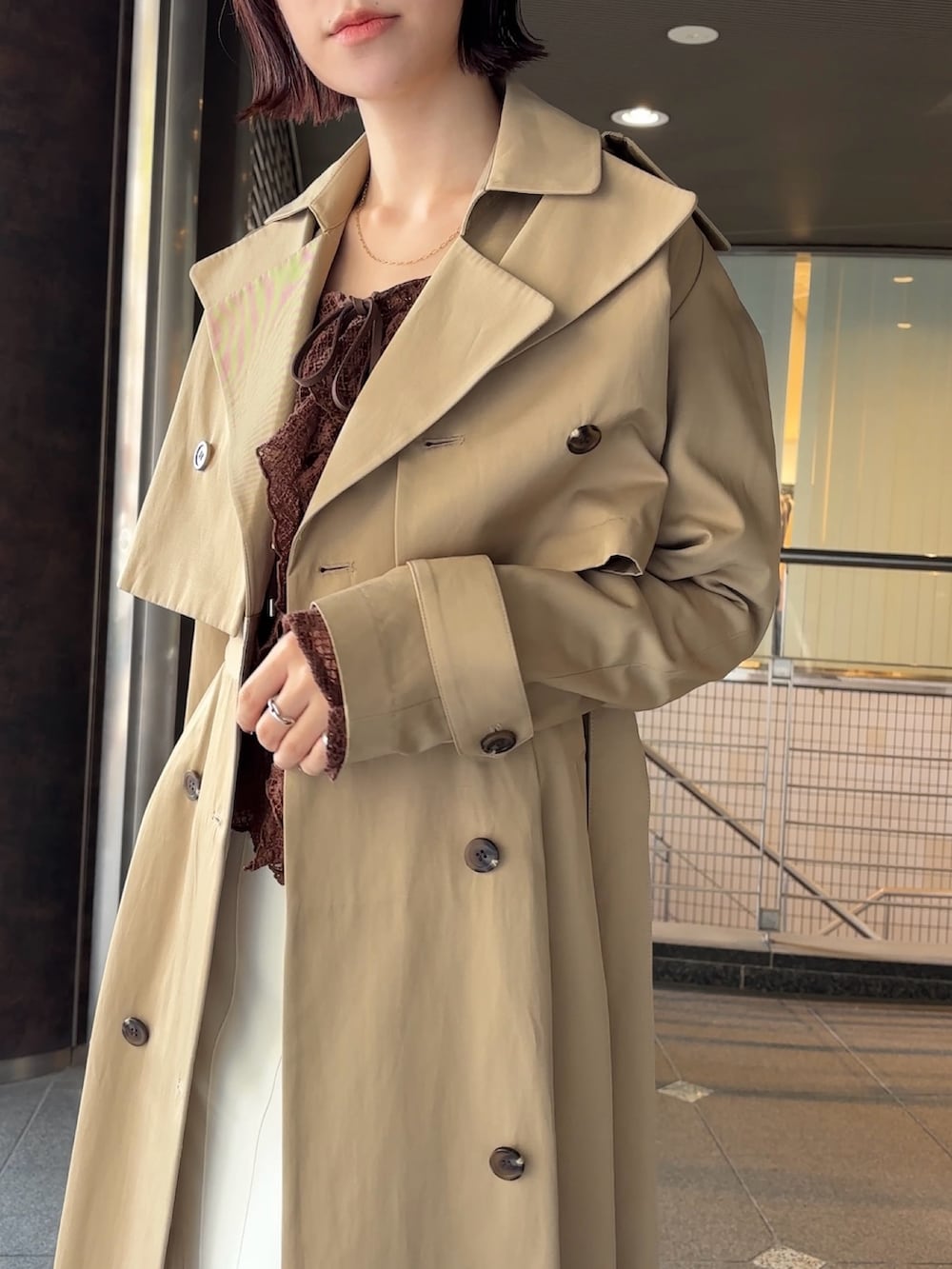 ブラウン系のシャツ/ブラウス、ベージュ系のトレンチコート、ブラウン系のハンドバッグを着用したレディースの冬コーディネートの5枚目の写真