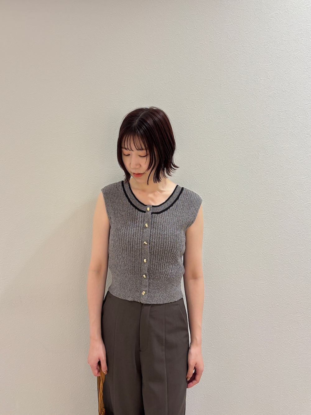 ブラウン系のその他パンツ、グレー系のニット/セーター、イエロー系のハンドバッグを着用したレディースの夏コーディネートの4枚目の写真