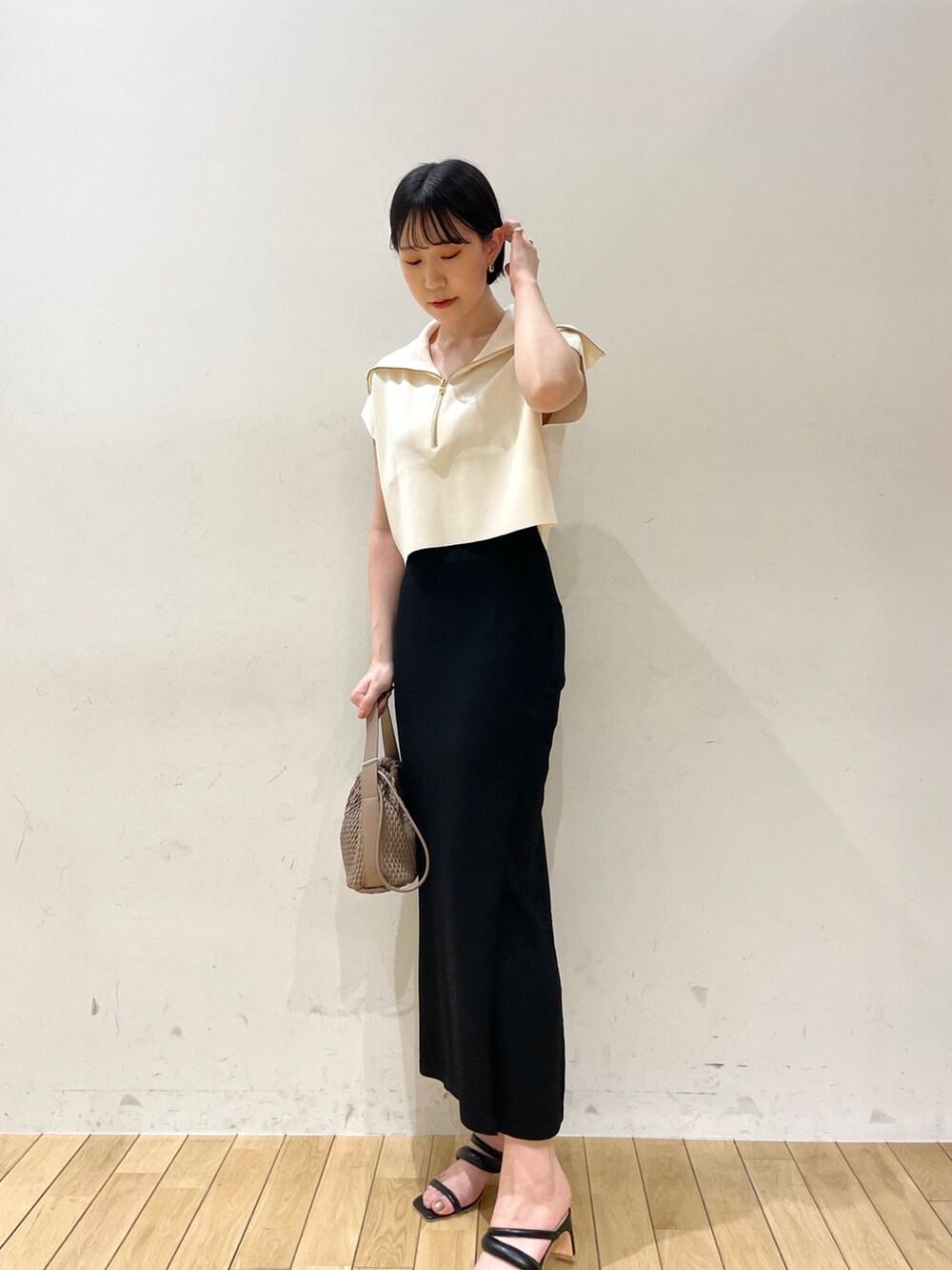 ブラック系のスカート、ホワイト系のニット/セーター、ブラウン系のハンドバッグを着用したレディースの春コーディネートの2枚目の写真