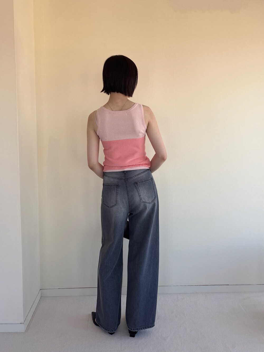 グレー系のデニムパンツ、ピンク系のニット/セーター、ブラック系のパンプスを着用したレディースの春コーディネートの3枚目の写真