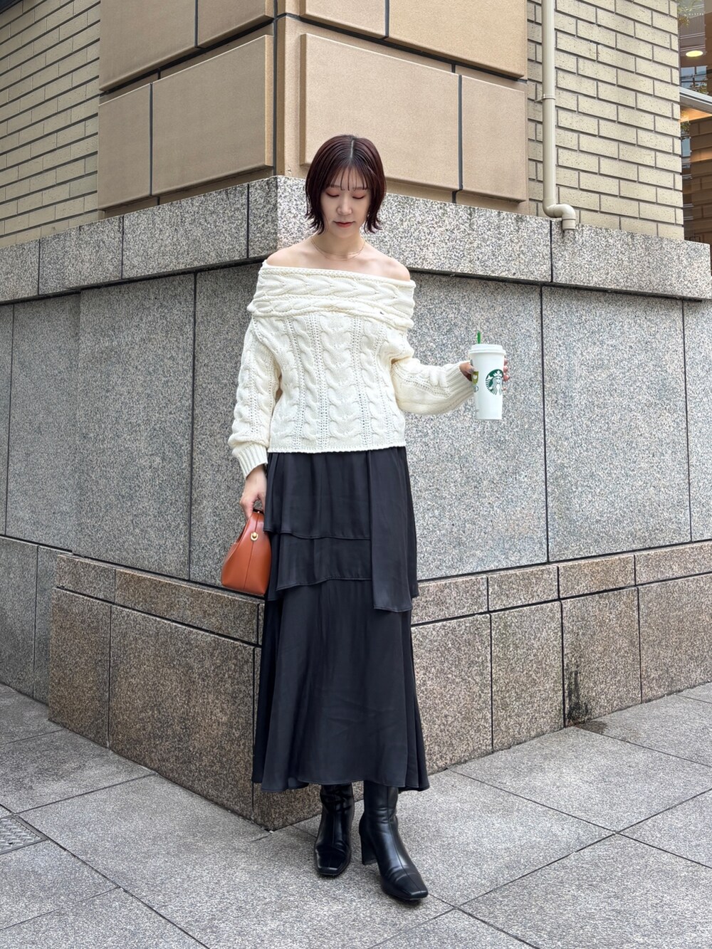 ホワイト系のニット/セーター、ブラック系のスカート、ブラウン系のハンドバッグを着用したレディースの秋コーディネートの2枚目の写真