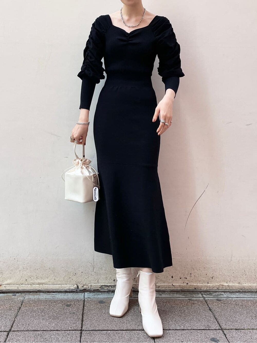 ブラック系のワンピース、ホワイト系のハンドバッグ、ホワイト系のその他シューズを着用したレディースの冬コーディネートの2枚目の写真