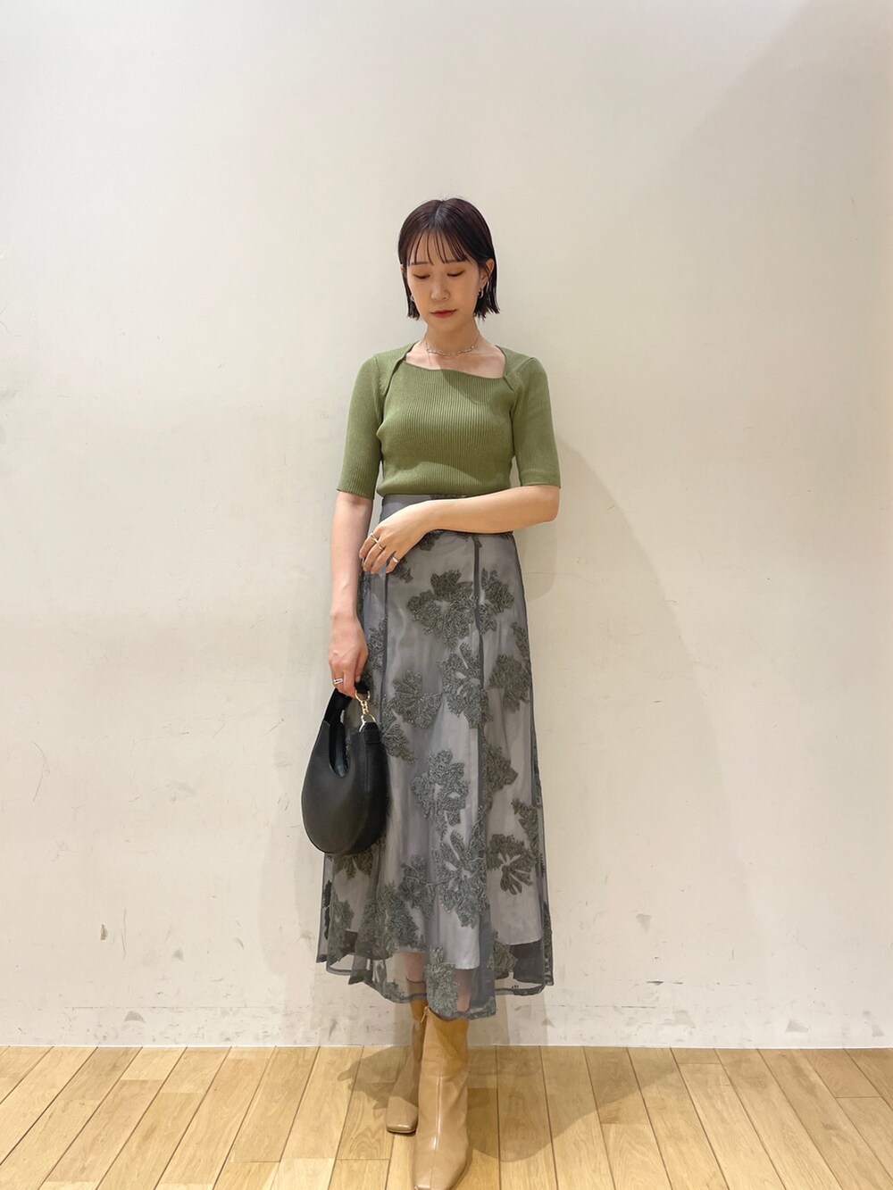 ベージュ系のブーツ、グリーン系のニット/セーター、グレー系のスカートを着用したレディースの夏コーディネートの3枚目の写真
