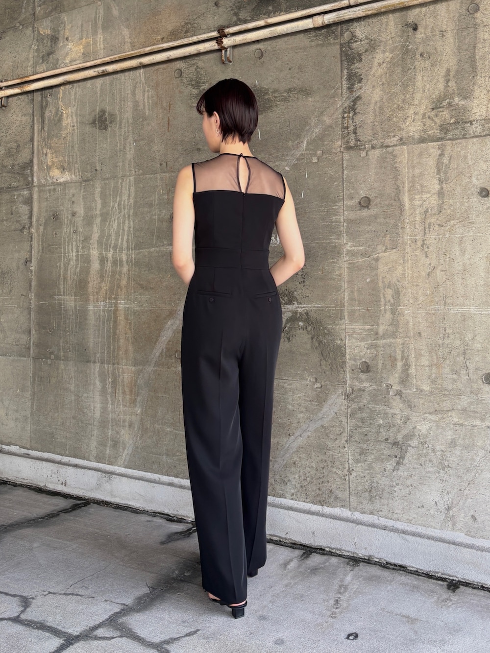 ブラック系のパンツドレス、シルバー系のショルダーバッグ、その他のパンプスを着用したレディースの春コーディネートの5枚目の写真