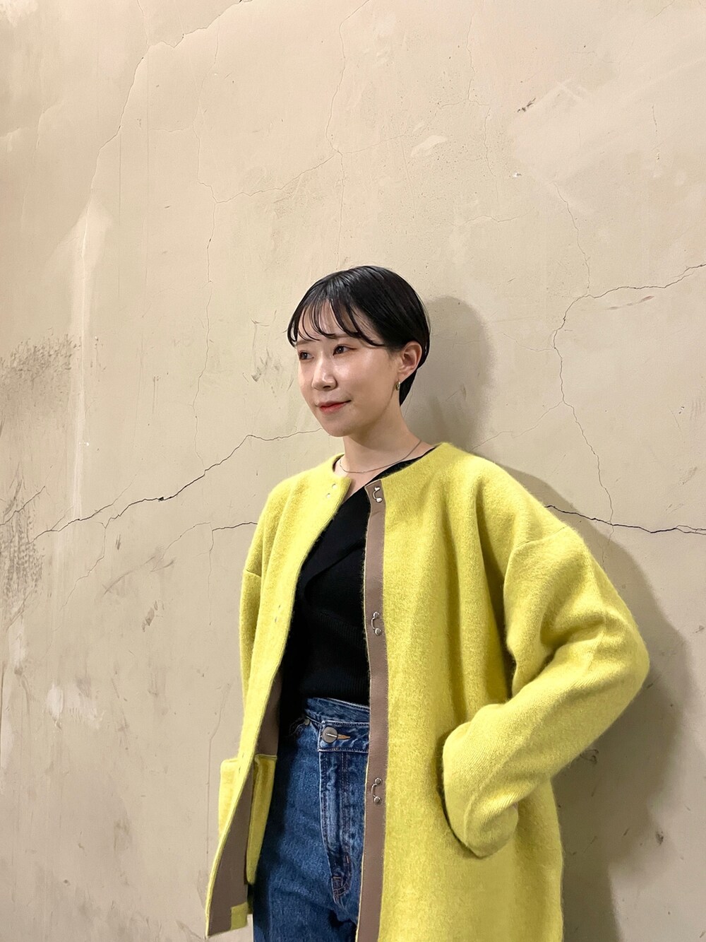 ブラック系のニット/セーター、イエロー系のカーディガン/ボレロ、ブルー系のデニムパンツを着用したレディースの秋コーディネートの4枚目の写真