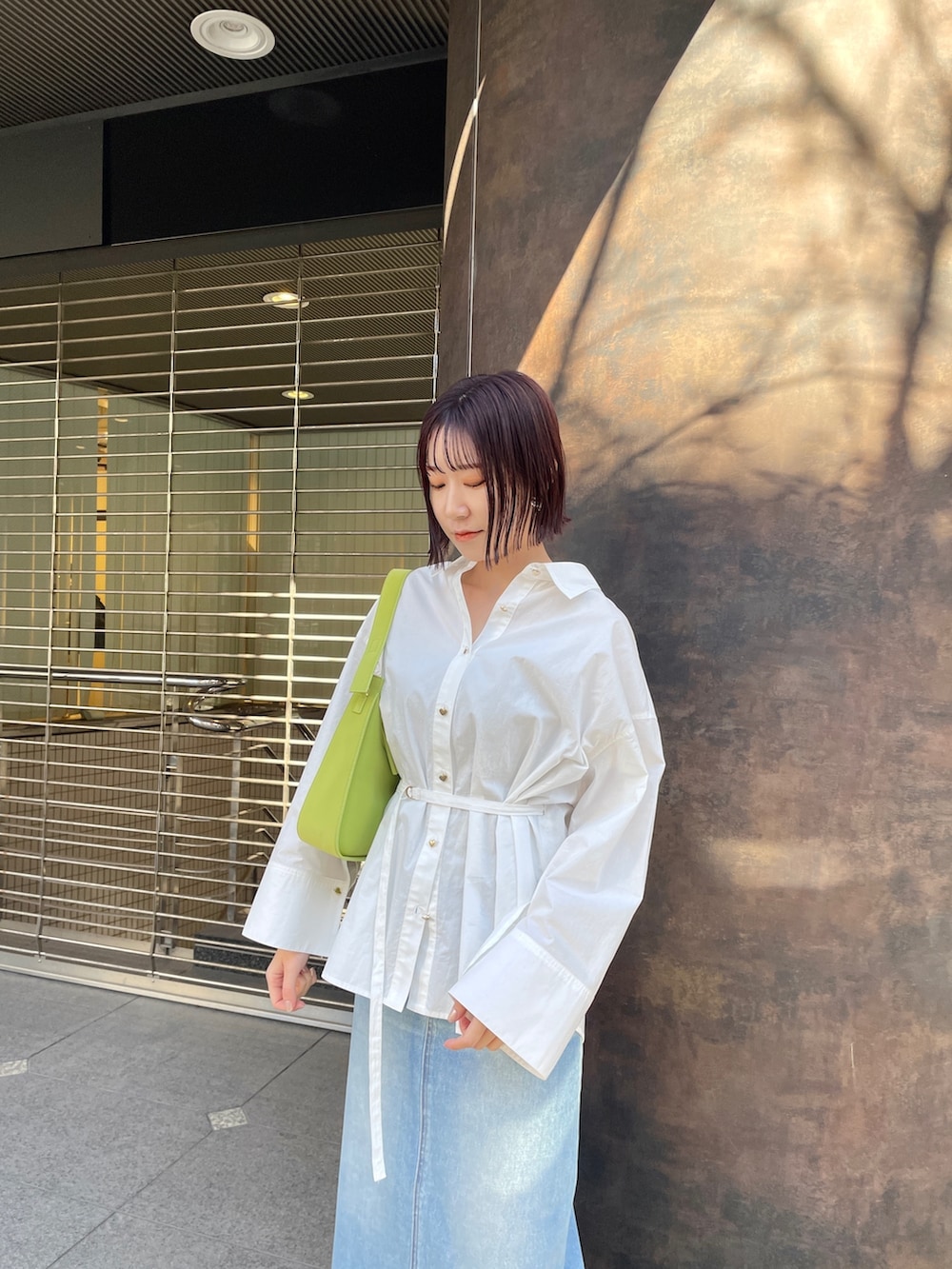 ホワイト系のシャツ/ブラウス、グリーン系のデニムスカート、ホワイト系のスニーカーを着用したレディースの春コーディネートの6枚目の写真