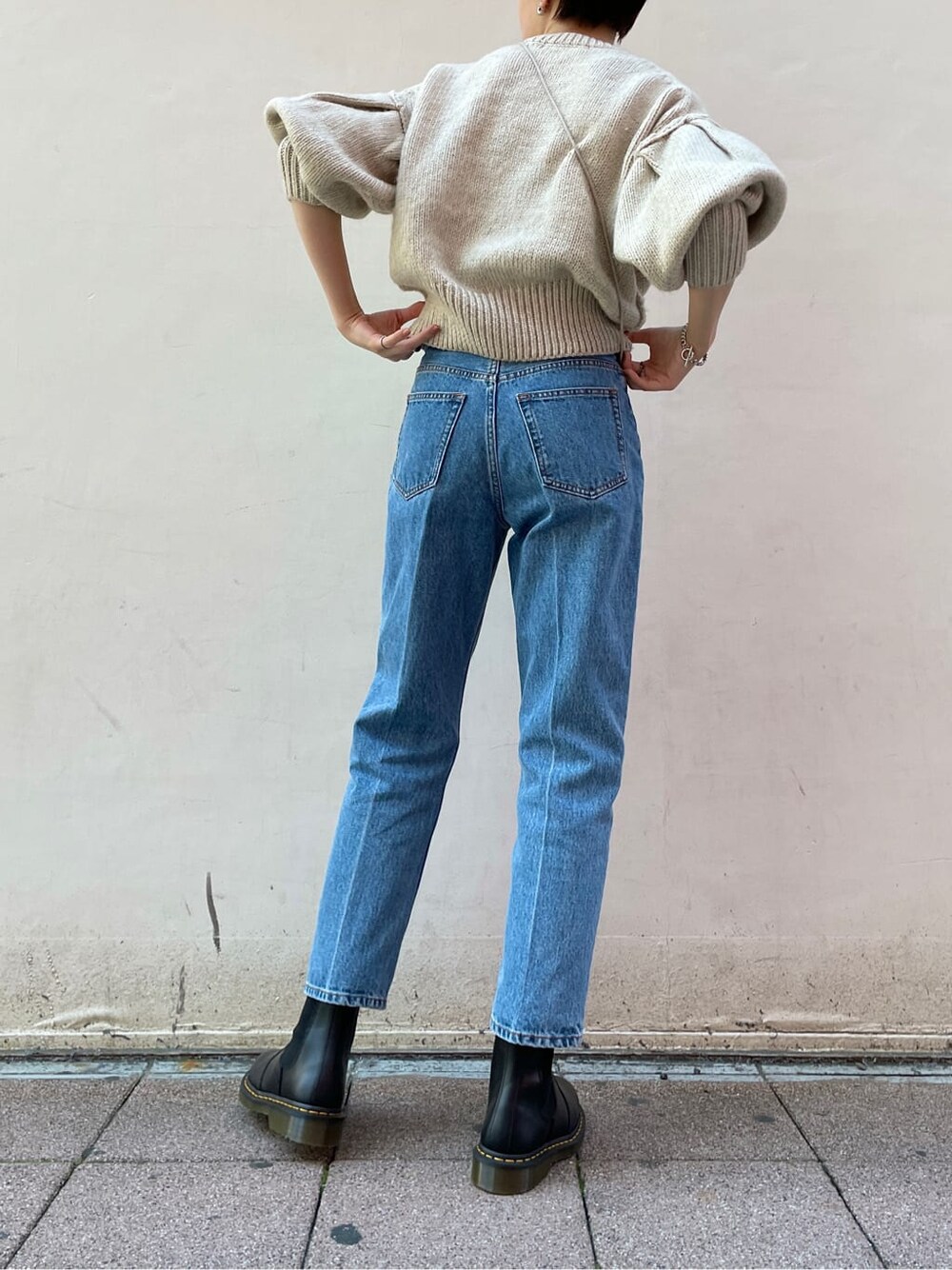 ブラック系のブーツ、ブルー系のデニムパンツ、ホワイト系のニット/セーターを着用したレディースの冬コーディネートの3枚目の写真