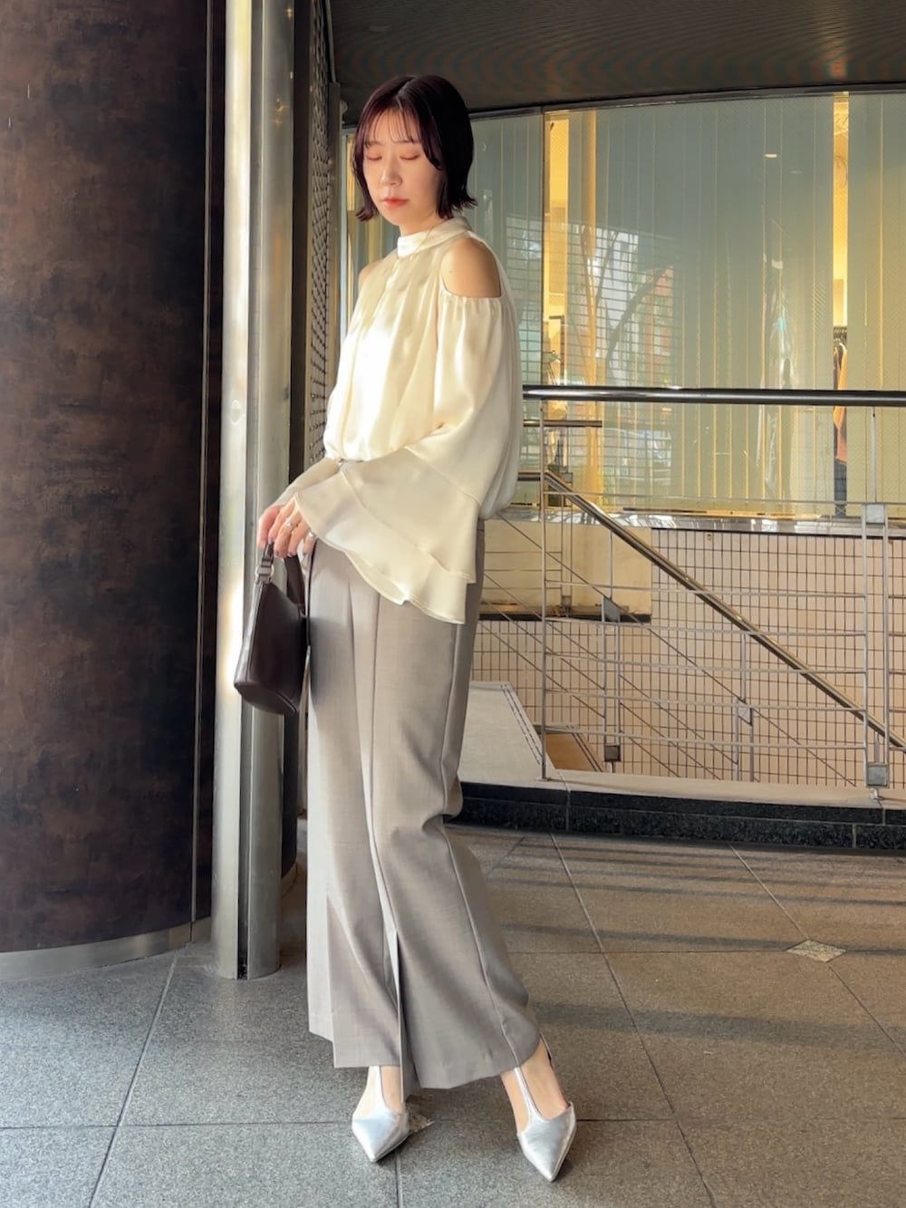 シルバー系のパンプス、ブラウン系のハンドバッグ、グレー系のその他パンツを着用したレディースの冬コーディネートの2枚目の写真