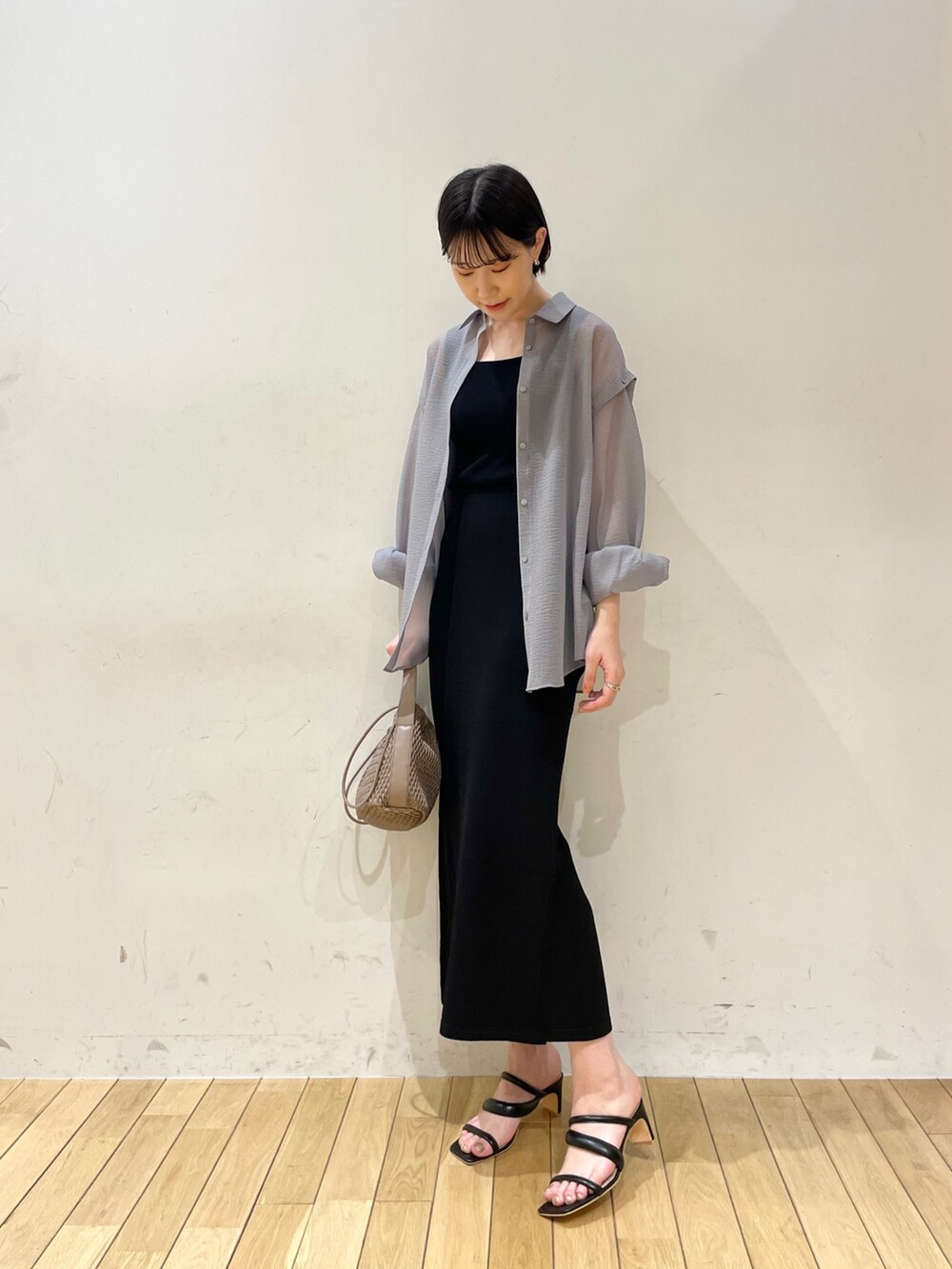 ブラック系のスカート、ブラウン系のハンドバッグ、ブラック系のサンダルを着用したレディースの春コーディネートの2枚目の写真