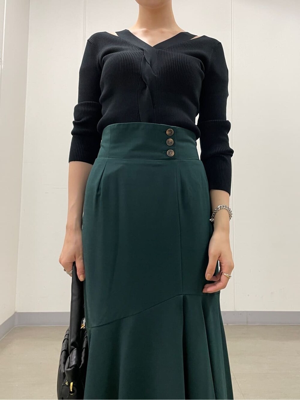 グリーン系のスカート、ブラック系のブーツ、ブラック系のニット/セーターを着用したレディースの秋コーディネートの5枚目の写真