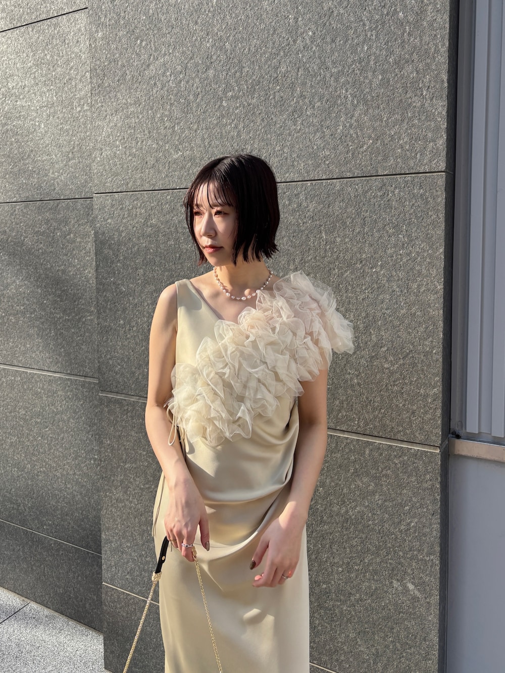 イエロー系のドレス、ブラック系のハンドバッグ、ブラック系のパンプスを着用したレディースの冬コーディネートの3枚目の写真