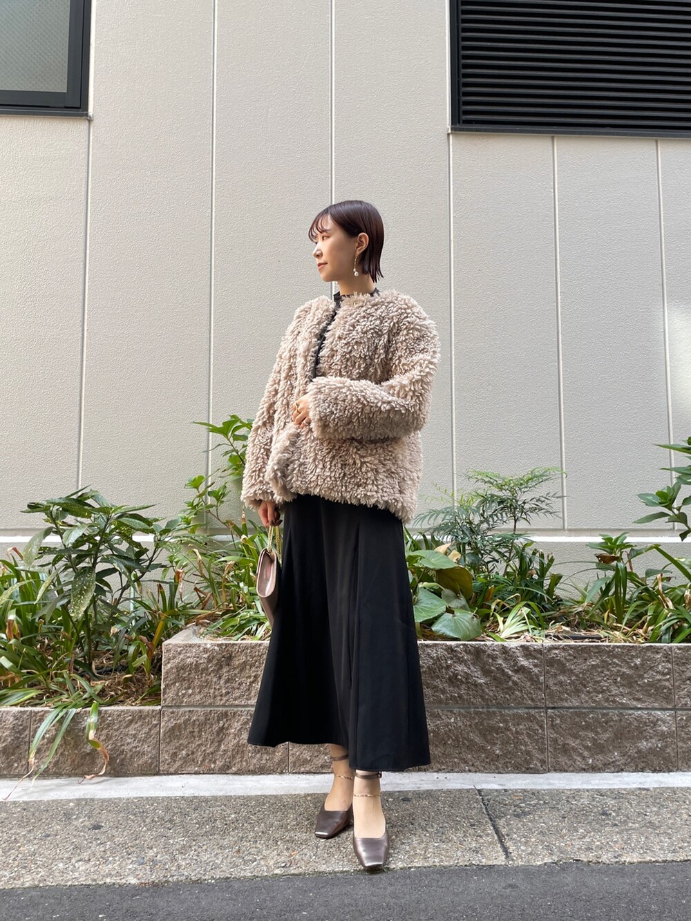 ブラック系のドレス、その他のパンプス、ゴールド系のハンドバッグを着用したレディースの秋コーディネートの8枚目の写真