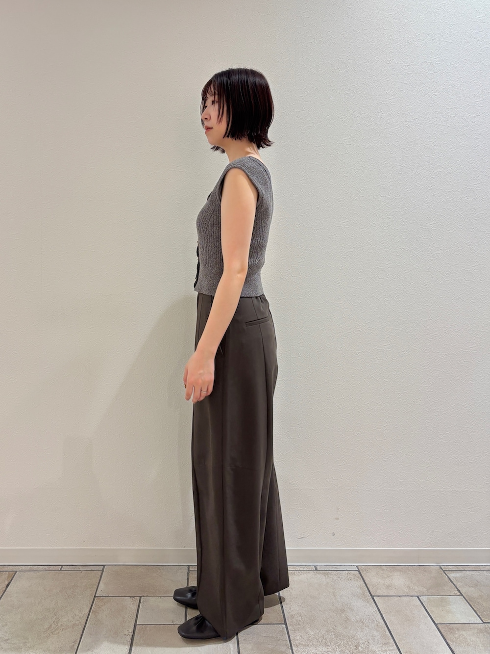 ブラウン系のその他パンツ、グレー系のニット/セーター、イエロー系のハンドバッグを着用したレディースの夏コーディネートの2枚目の写真